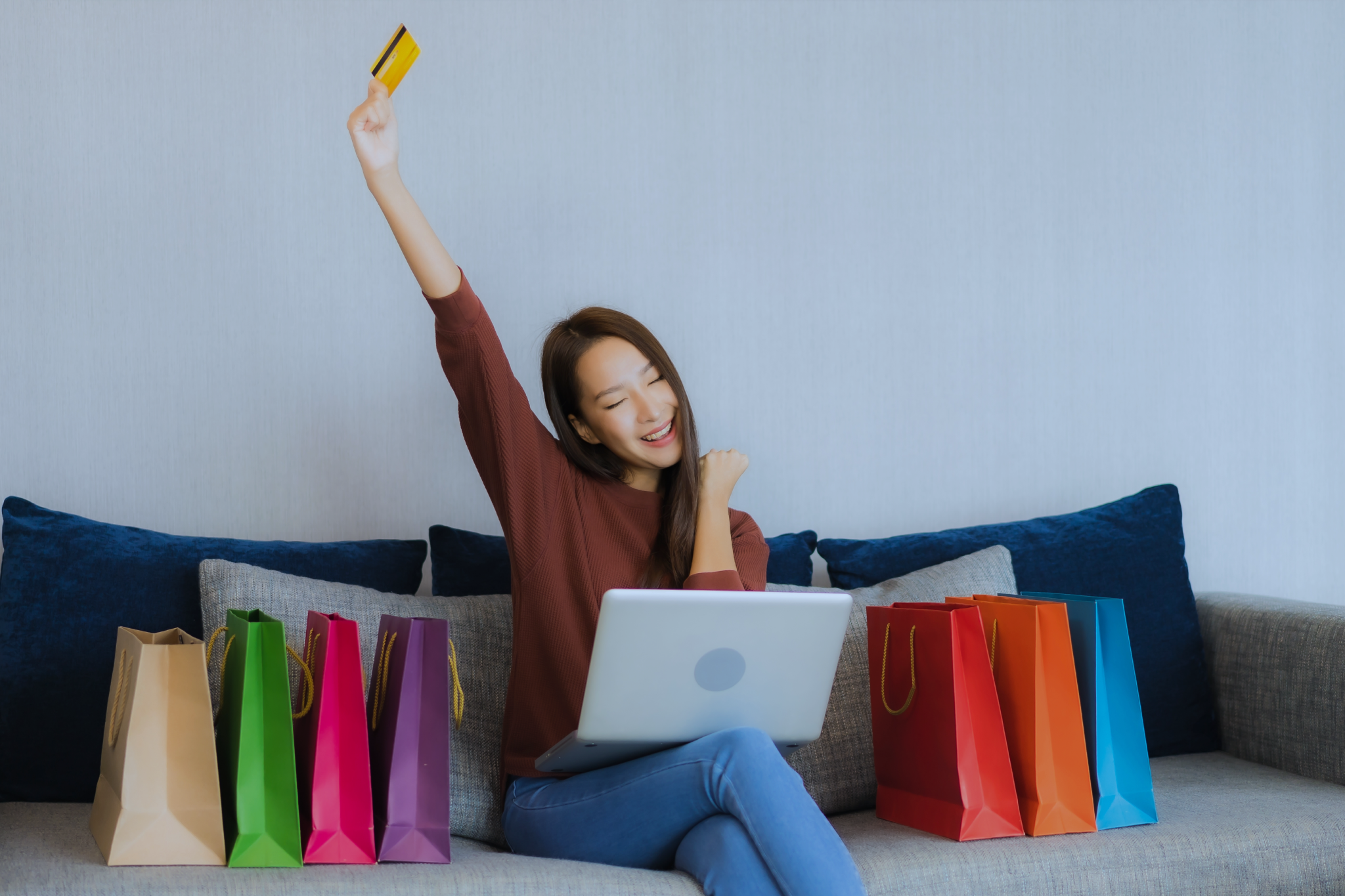 Pessoa alegre fazendo compras online com um notebook no colo